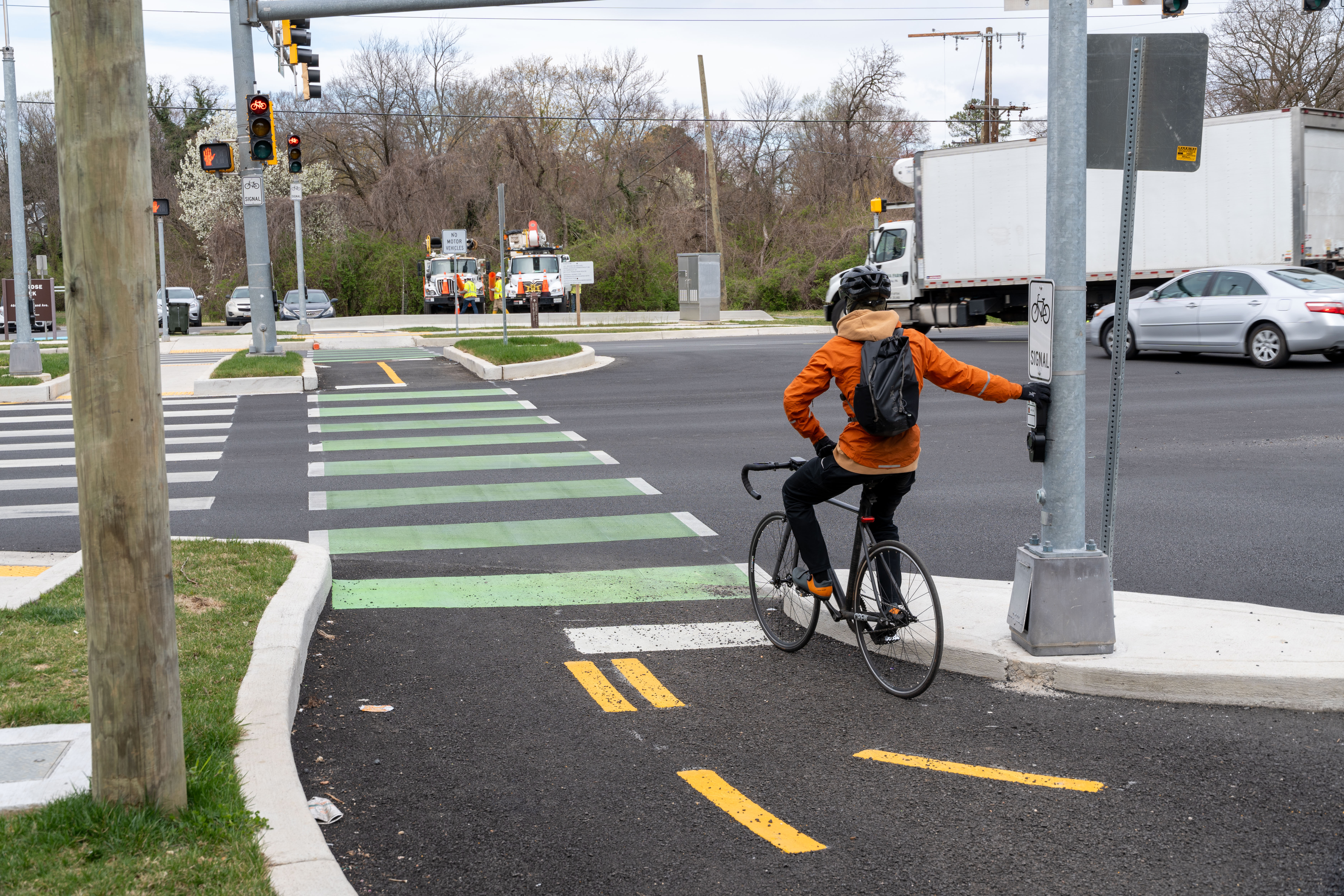 Bicyclist waits at light at busy cross roads.