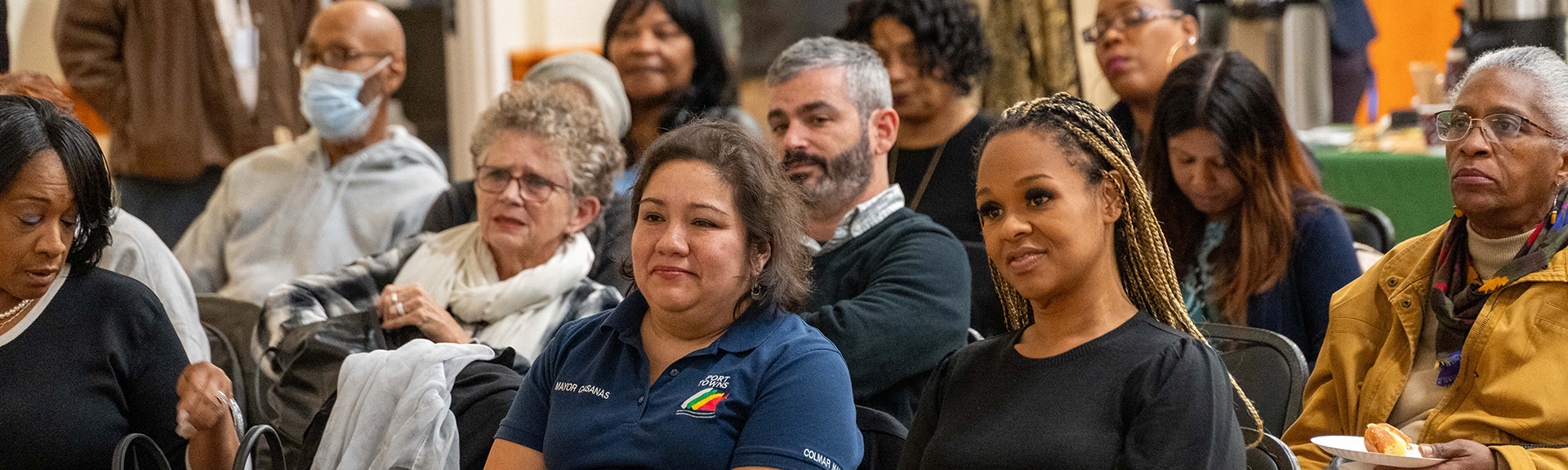 A group of people seated, listening to a meeting presentation.