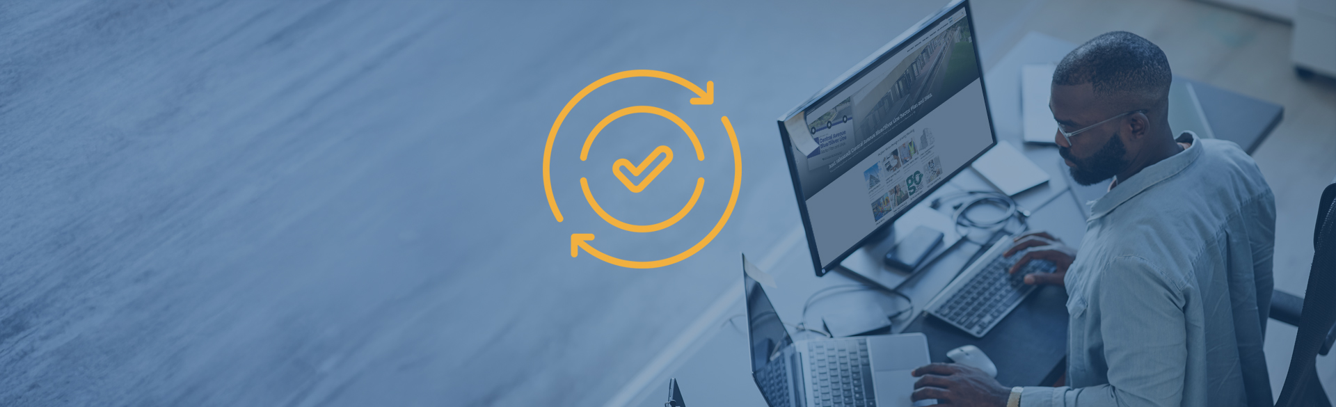 man works at computer, update symbol in center of screen.