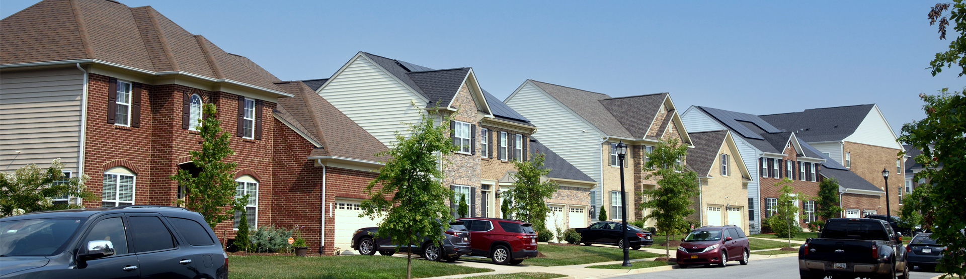 Houses line a neighborhood street with cars parked in driveways and along the side of the street in Westphalia.