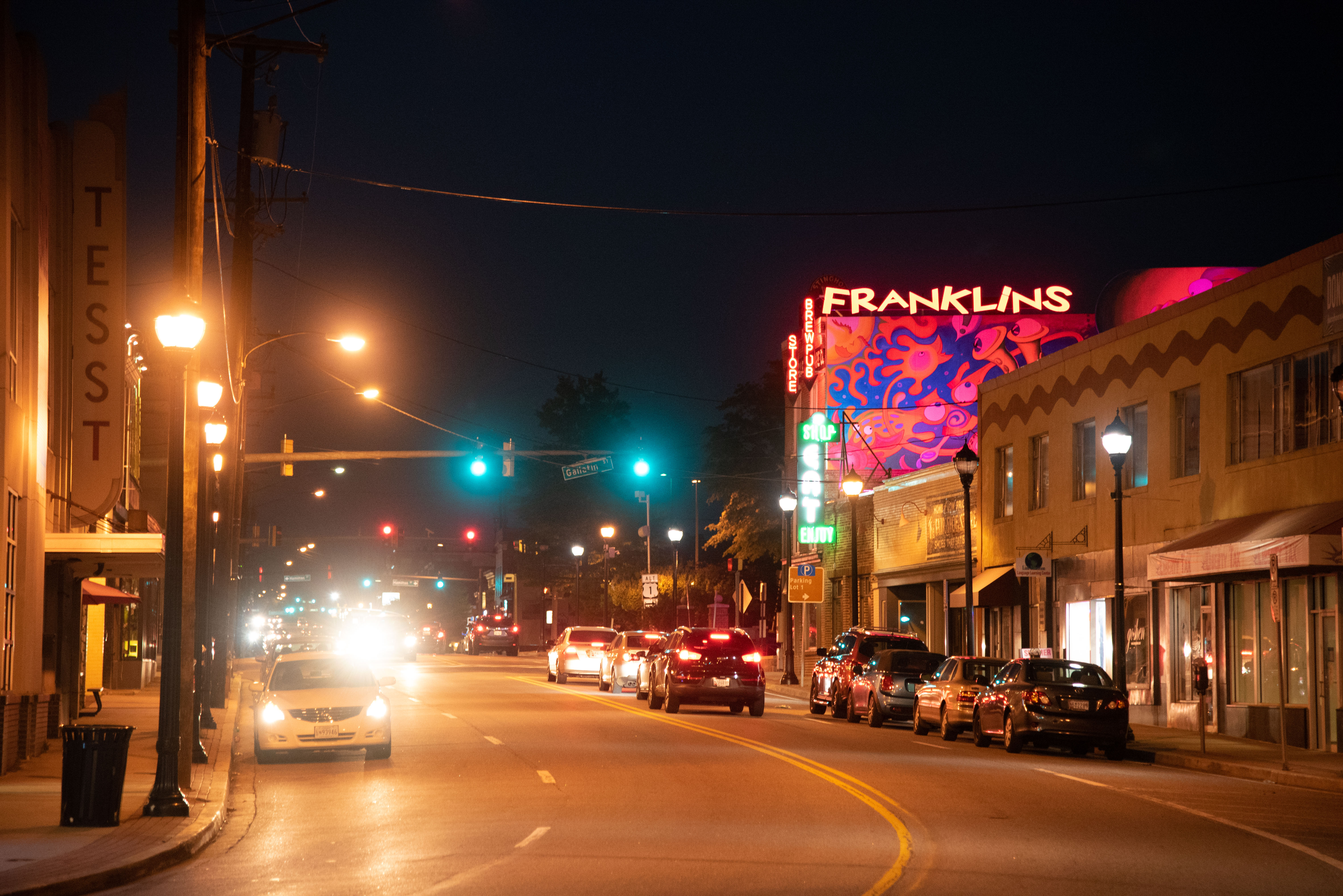 The street outside of Franklin's Restaurant, in Hyattsville, Maryland, at night. Bright lights blurred from cars and street lamps.