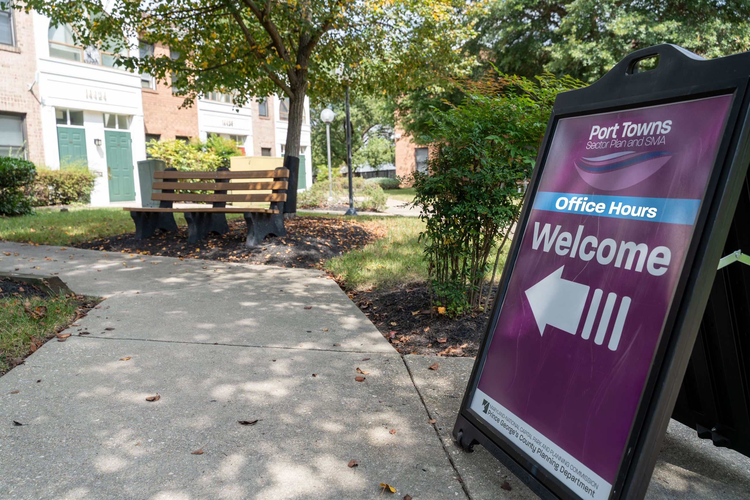 A purple welcome sign with arrow for the Port Towns Sector Plan Office Hours event.