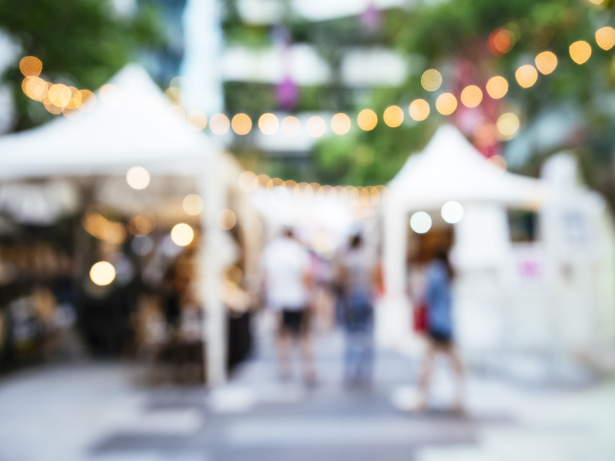 A blurred background of tents, lights, and people celebrating.