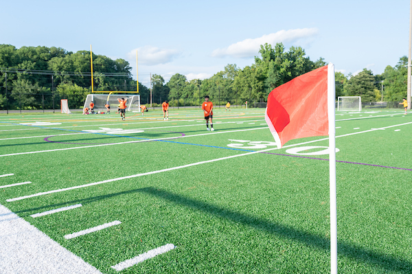 A soccer turf field with flags and players on it.