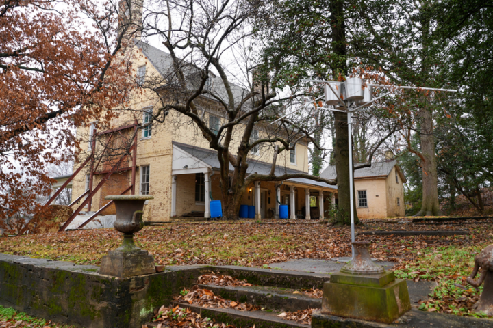 Yellow historic house with leaves on the ground and stairs