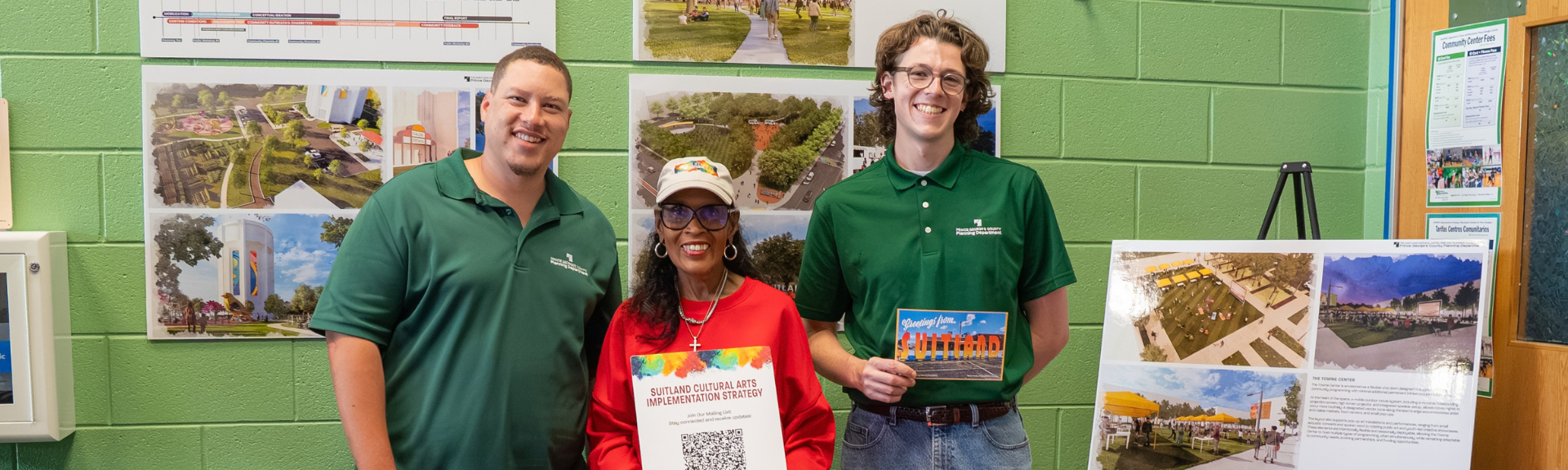 Community planners at the Suitland Cultural Arts meeting stand before posters and illustratives about the project.